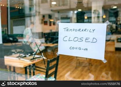 Coffee shop closed by covid-19 with workers picking up and cleaning inside. Coffee shop closed by covid-19