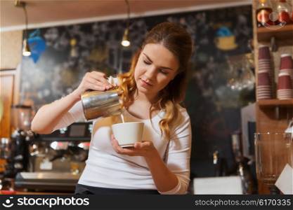 coffee shop, occupation, drinks, people and technology concept - barista woman pouring cream to cup at cafe bar or restaurant kitchen