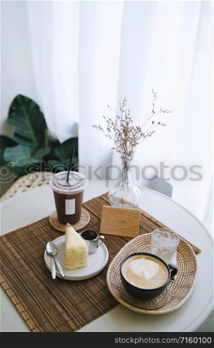 Coffee table, iced and hot coffee drink with tasty cake on the table in cozy cafe style, minimal and hipster style