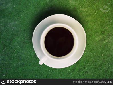 Coffee time. Close up of coffee cup on green surface