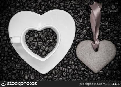 Coffee time concept. Heart shaped cup plate and cookie gingerbread on coffee beans background. Black white photo.