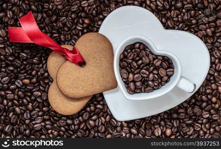 Coffee time concept. Heart shaped cup plate and cookie gingerbread on coffee beans background. Top view