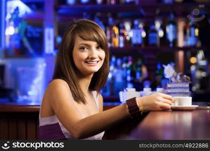 Coffee time. Young pretty lady sitting at bar with cup of coffee