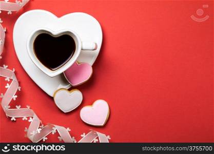 Coffee with cookie in shape of heart on red background. Composition for Valentines Day. Top view. Copy space