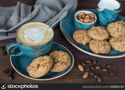 Coffee with cream in blue vintage cup and cookies on a old dark wooden boards
