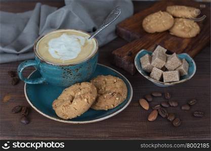 Coffee with cream in blue vintage cup and cookies on a old dark wooden boards