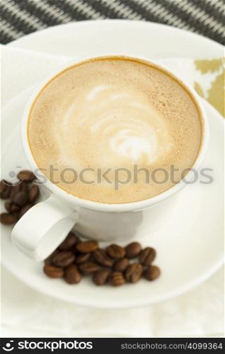 Coffee with foam and beans on the table