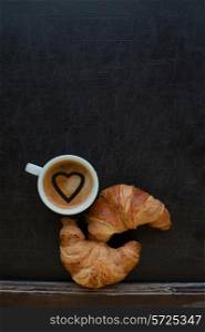 coffee with hearts and croissant at board