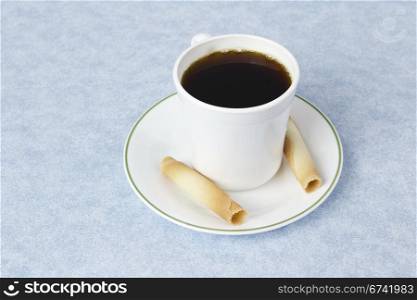 Coffee with saucer, cup and treats on blue table cloth