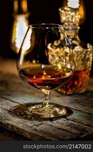 Cognac and carafe on old wooden table and a background of vintage lamps. Cognac and carafe