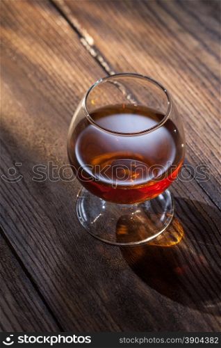 Cognac in glass on the wooden surface. Cognac in glass on the wood