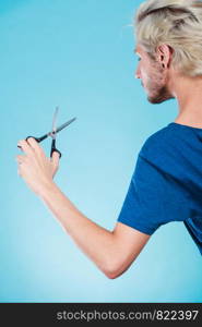 Coiffure hairstyle and haircut. Young cool guy holding special shears tool for work of hairdresser, on blue. Man with scissors texturizing or thinning shears