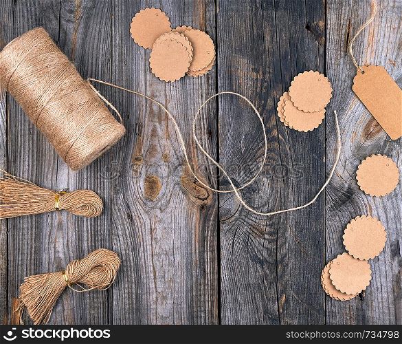 coil of brown rope, paper tags on a gray wooden background, objects for making handicrafts