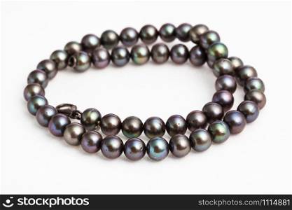 coiled necklace from natural black pearls on white paper background