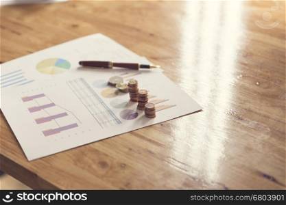 coin, pen and business document on wooden table, selective focus and vintage tone