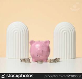 coins and pink piggy bank on a white table. Concept of accumulating cash, saving, receiving subsidies