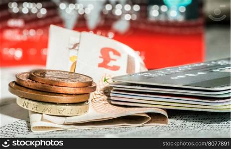 Coins, credit cards and british pounds on newspaper. Macro shot