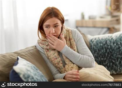 cold and health problem concept - sick woman in scarf and blanket coughing at home. sick woman in scarf coughing at home