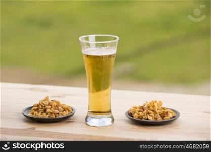 Cold beer with roasted peanuts, on wooden table, outdoor