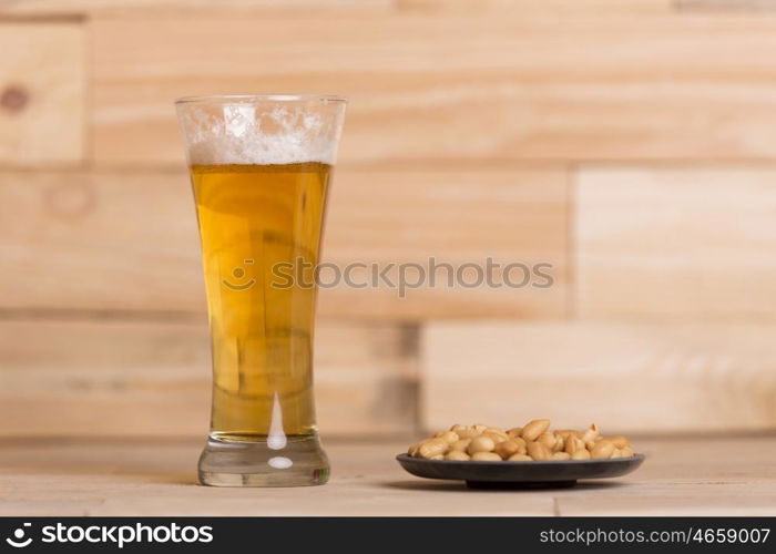 Cold beer with roasted peanuts, on wooden table, Still Life style