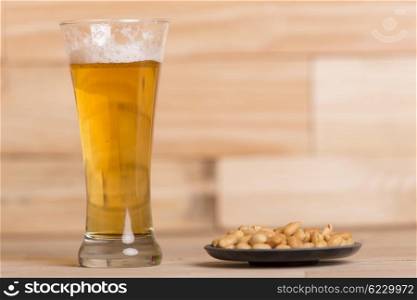 Cold beer with roasted peanuts, on wooden table, Still Life style