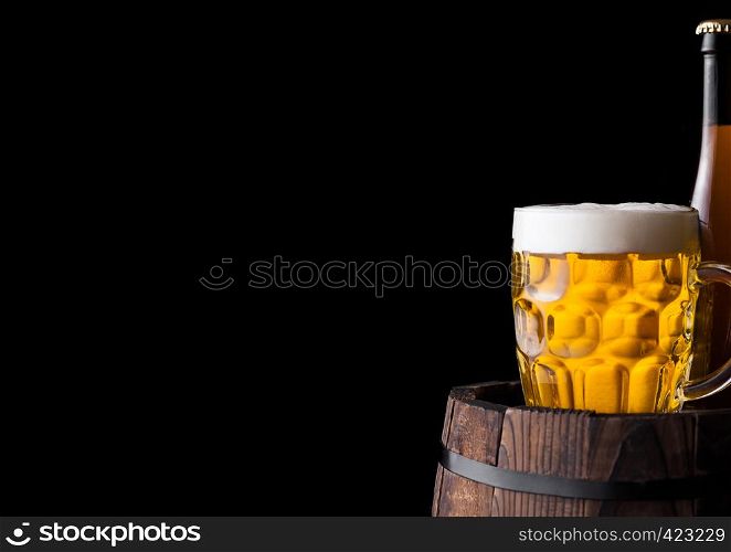 Cold bottle and glass of craft beer on old wooden barrel on black background