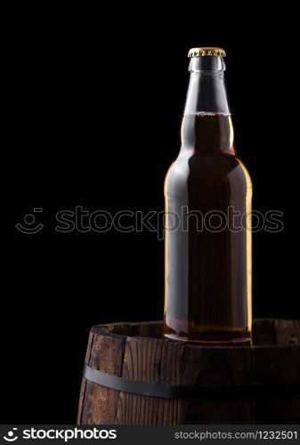 Cold bottle of craft beer on old wooden barrel on black background