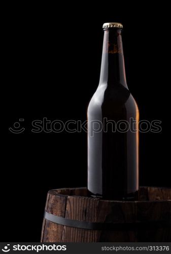 Cold bottle of craft beer on old wooden barrel on black background