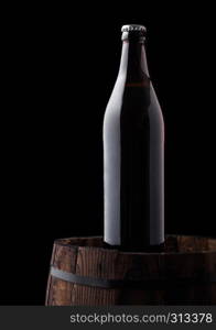 Cold bottle of craft beer on old wooden barrel on black background