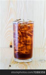 Cold cola in glass on the wooden floor.
