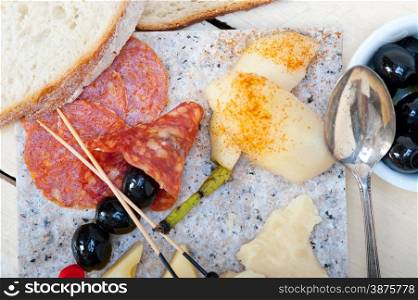 cold cut assortment cheese salami and fresh pears served on a granite stone