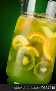 cold drink of citrus in a decanter on a green background. summer tropical juice. summer fruit drink