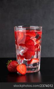 Cold drink with strawberries on a black background. Summer berry detox beverage in a glass. Place for text.. Cold drink with strawberries on black background. Summer berry detox beverage in a glass. Place for text.