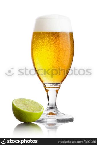 Cold fresh glass of beer with foam and lime slice on white background