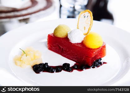 Cold fresh watermelon and mixed fruits ice cream sorbet on top with sweet and sour berries sauce in white plate - summer healthy dessert