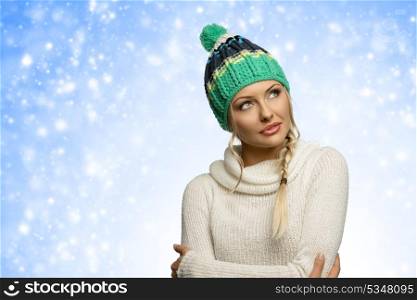 cold girl in winter dress , with green hat arming herself in act to warm and looking away with eyes