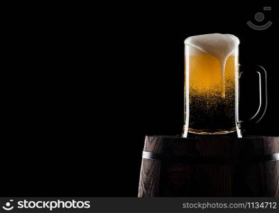 Cold glass of craft beer on old wooden barrel on black background with dew and bubbles. With space for your text.