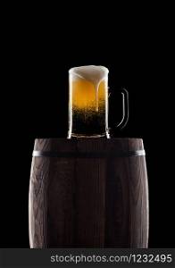 Cold glass of craft beer on old wooden barrel on black background with dew and bubbles