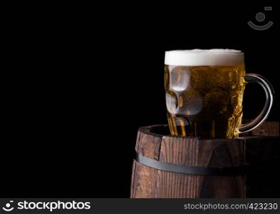 Cold glass of craft beer on old wooden barrel on black background