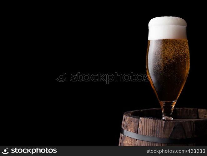 Cold glass of craft beer on old wooden barrel on black background