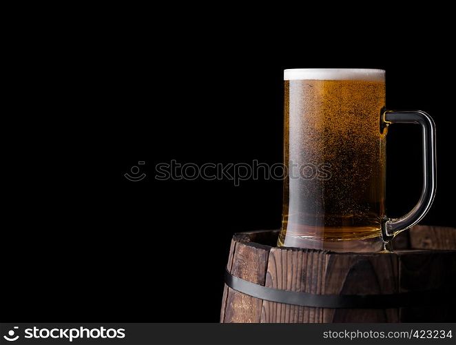 Cold glass of craft beer on old wooden barrel on black background
