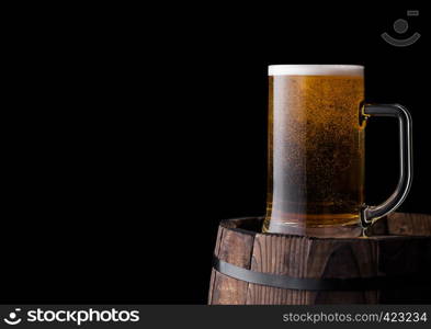 Cold glass of craft beer on old wooden barrel on black background