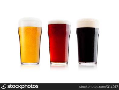 Cold glasses of lager stout and red beer with foam and dew on white background with reflection
