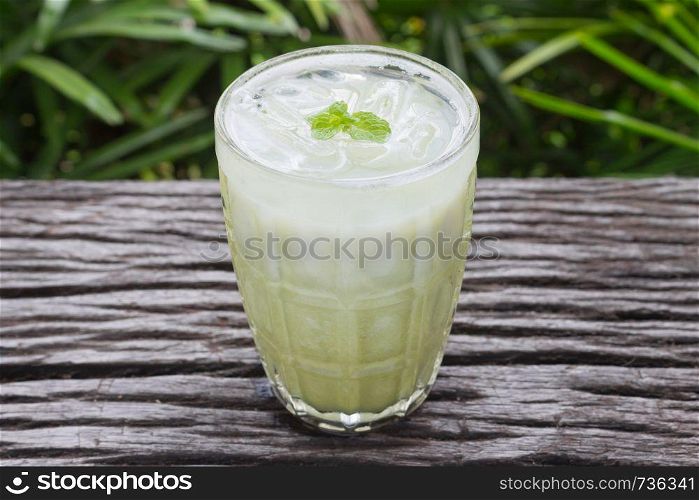 Cold Green Tea Milk Beverage or Cold Drinks Center Frame. Green cold drinks and ice on wood table for drink