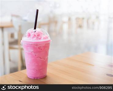 Cold milk smoothie in a plastic cup on a wooden table and has sunlight a beautiful background.
