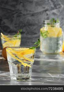 Cold refreshing drink or beverage with ice on dark background. Two glass with lemonade or mojito cocktail with lemon and mint. Copy space