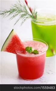 Cold refreshing drinks with watermelon and green cocktail in a glasses on white marble background.