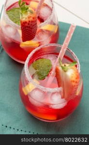 Cold strawberry drink with fresh strawberries and lemon on wooden background