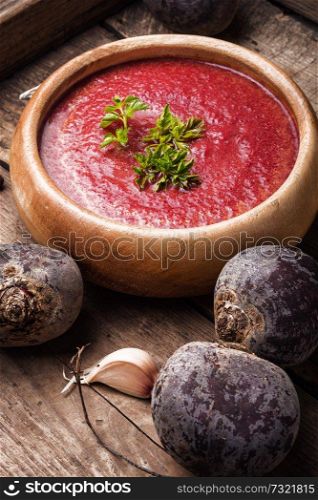 Cold summer beets soup on wooden table. Beetroot creamy soup