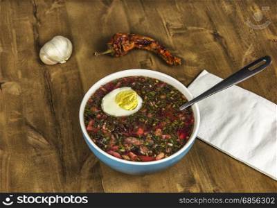 Cold vegetable soup with egg on a wooden table